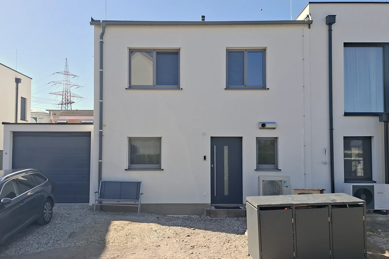 Die fertige Doppelhaushälfte in Massivholzbauweise in Asten von der Straßenseite: links die Garage, in der Mitte der Hauseingang, rechts unmittelbar angebaut das Nachbarhaus